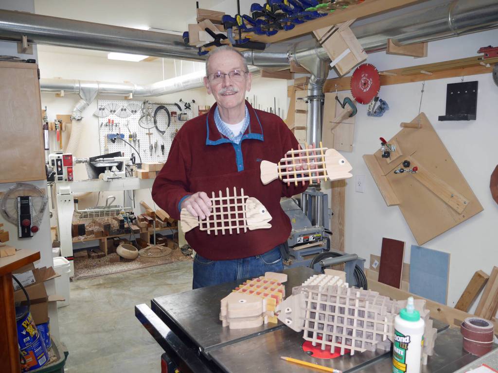 Homer woodworker Ted Heuer in photographed in his shop with rockfish and halibut trivets in 2022. Photo by Beth Heuer