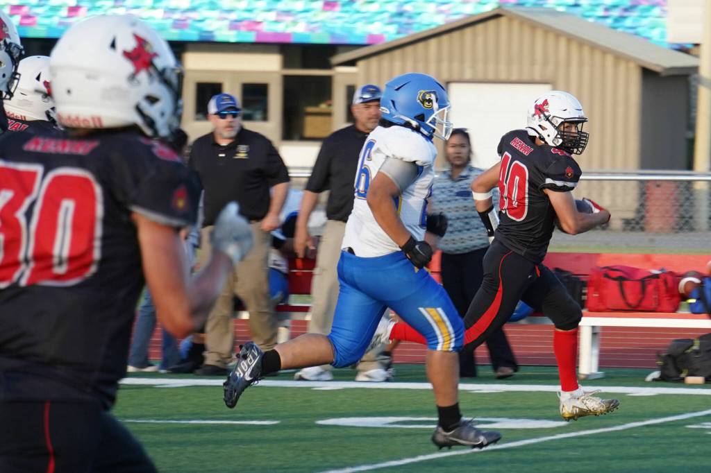 Kenais Bobby Hayes runs with the ball, closely pursued by Kodiaks Jet Jered Mendoza during a season opening game at Ed Hollier Field in Kenai, Alaska, on Friday, Aug. 11, 2023. (Jake Dye/Peninsula Clarion)