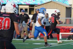 Kenais Bobby Hayes runs with the ball, closely pursued by Kodiaks Jet Jered Mendoza during a season opening game at Ed Hollier Field in Kenai, Alaska, on Friday, Aug. 11, 2023. (Jake Dye/Peninsula Clarion)