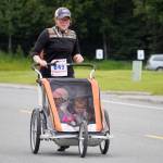 Amanda Mayner pushes a stroller while racing toward the finish chute of the 34th Annual Kenai Peninsula Violence Free Community Run in Kenai, Alaska, on Saturday, Aug. 12, 2023. (Jake Dye/Peninsula Clarion)