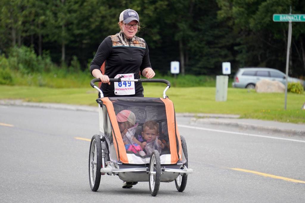 Amanda Mayner pushes a stroller while racing toward the finish chute of the 34th Annual Kenai Peninsula Violence Free Community Run in Kenai, Alaska, on Saturday, Aug. 12, 2023. (Jake Dye/Peninsula Clarion)