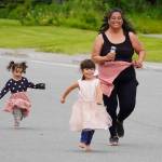 A participant, joined by children, races to the finish chute of the 34th Annual Kenai Peninsula Violence Free Community Run in Kenai, Alaska, on Saturday, Aug. 12, 2023. (Jake Dye/Peninsula Clarion)