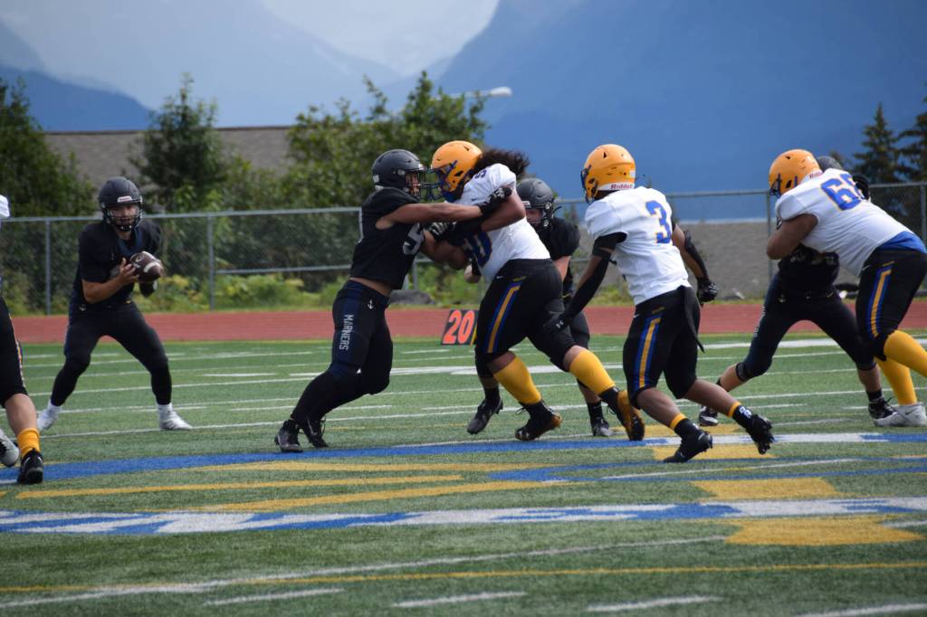 A Homer High Mariner blocks the Barrow Whalers Norm Lilomaiava at the home opener varsity football game on Saturday, Aug. 12, 2023 in Homer, Alaska. (Delcenia Cosman/Homer News)