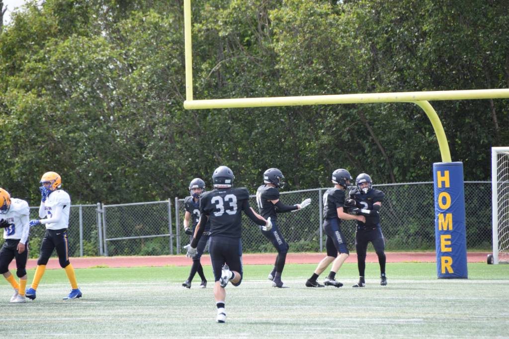 Chris Martishevs teammates congratulate him after he caught a 58-yard pass from quarterback Preston Stanislaw, scoring a touchdown and bringing the Mariners score up to eight points in the first quarter of the home opener varsity game on Saturday, Aug. 12, 2023 in Homer, Alaska. (Delcenia Cosman/Homer News)