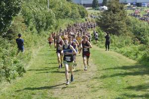 Erik Thompson of Juneau-Douglas: Yadaa.at Kale leads the pack up a hill at the beginning of the boys varsity race at the Ted McKenney Invitational on Saturday, Aug. 19, 2023, at Tsalteshi Trails just outside of Soldotna, Alaska. (Photo by Jeff Helminiak/Peninsula Clarion)