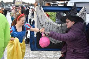 A girl dressed as Snow White takes candy from a witch at the Orca Theaters Trunk or Treat in Soldotna, Alaska on Monday, Oct. 31, 2022. (Jake Dye/Peninsula Clarion)