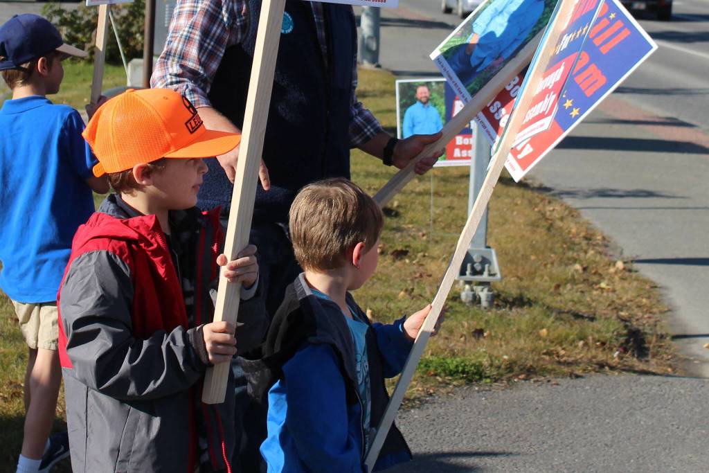 James Elam, left, and Andrew Elam, right, wave signs for their dad, Kenai Peninsula Borough Assembly candidate Bill Elam, on election day on Tuesday, Oct. 3, 2023, in Soldotna, Alaska. (Ashlyn OHara/Peninsula Clarion)