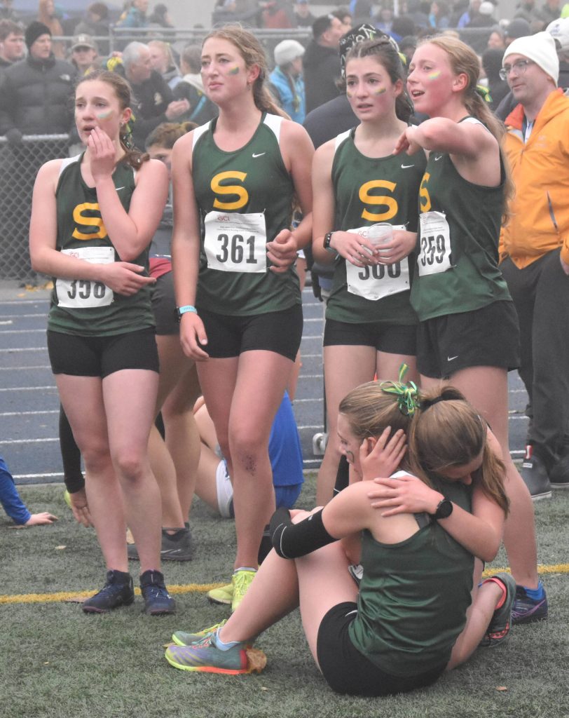 Sewards Selah Brueckner, Katie Van Buskirk, Maddie Haas and Juniper Ingalls try to figure out if they won by looking at the scoreboard Saturday, Oct. 7, 2023, in the Division II girls state cross-country race at Palmer High School in Palmer, Alaska. (Photo by Jeff Helminiak/Peninsula Clarion)