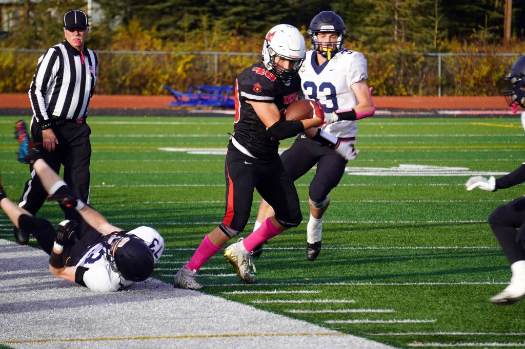 Kenais Bobby Hayes moves with the ball while evading Homers Joe Gordon and Jake Tappan during a Division III playoff game at Justin Maile Field in Soldotna, Alaska, on Saturday, Oct. 7, 2023. (Jake Dye/Peninsula Clarion)