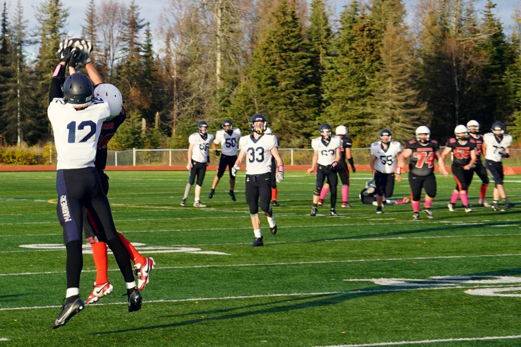 Homers CJ Burns and Kenais Cole Langham leap for the ball during a Division III playoff game at Justin Maile Field in Soldotna, Alaska, on Saturday, Oct. 7, 2023. (Jake Dye/Peninsula Clarion)
