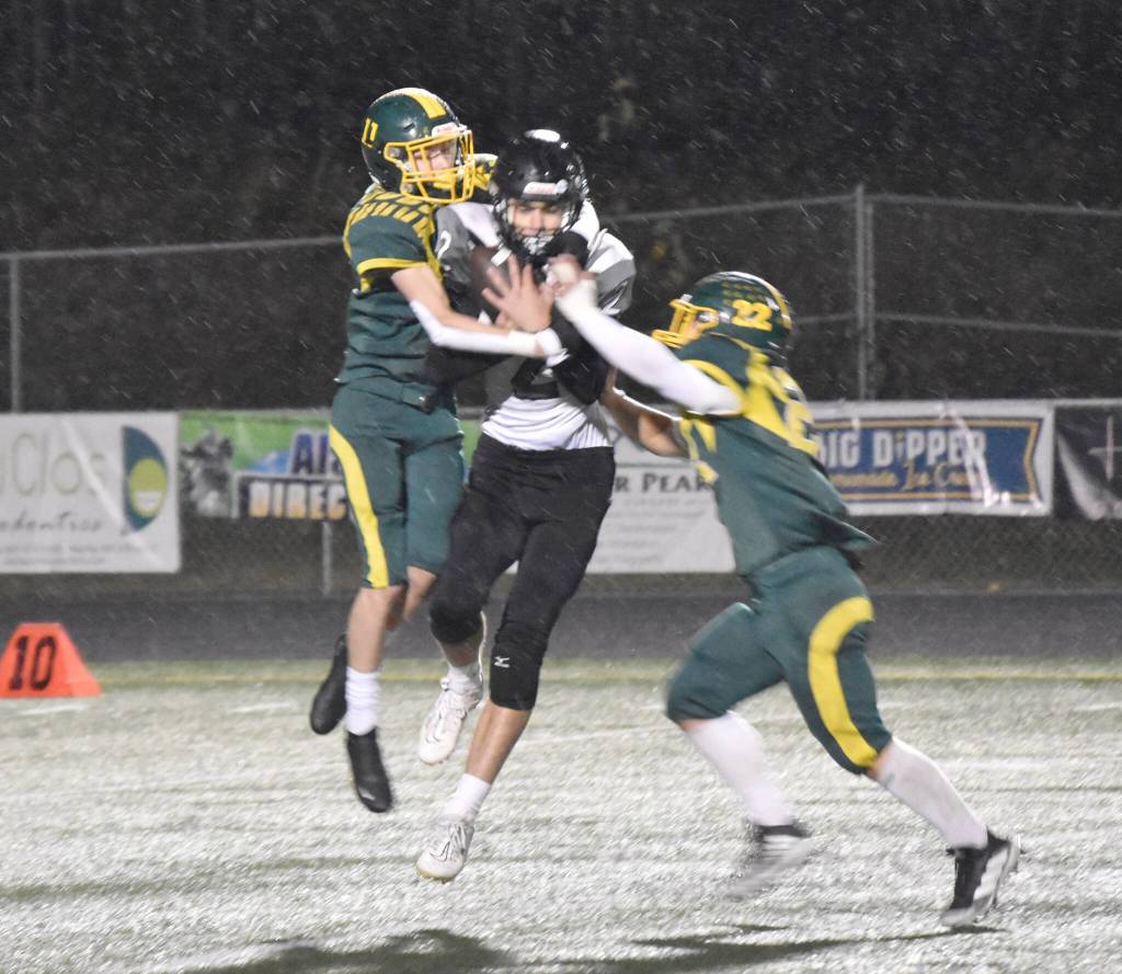 Nikiskis Seth Payne makes a catch between Sewards Hunter Forshee-Kurtz and Noah Price on Saturday, Oct. 7, 2023, in the nine-man football state final at Colony High School in Palmer, Alaska. (Photo by Jeff Helminiak/Peninsula Clarion)