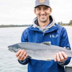 A participant of Catching for a Cause holds aloft a salmon. (Photo courtesy Josiah Martin/Kenai Peninsula Food Bank)