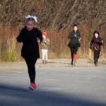 Juniper Pilatti leads a small pack as she approaches the finish chute of the Costume Caper at Nikiski Community Recreation Center in Nikiski, Alaska, on Saturday, Oct. 21, 2023. (Jake Dye/Peninsula Clarion)