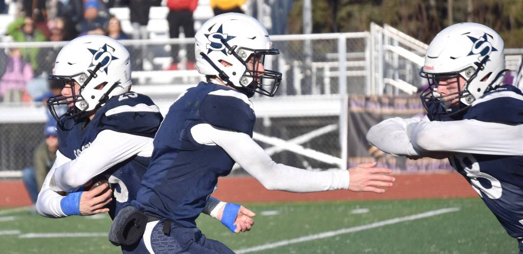 After handing to Soldotnas Gehret Medcoff for a 91-yard touchdown run, quarterback Zac Buckbee fakes a handoff to Collin Peck on Saturday, Oct. 21, 2023, in the Division II championship game at Service High School in Anchorage, Alaska. (Photo by Jeff Helminiak/Peninsula Clarion)