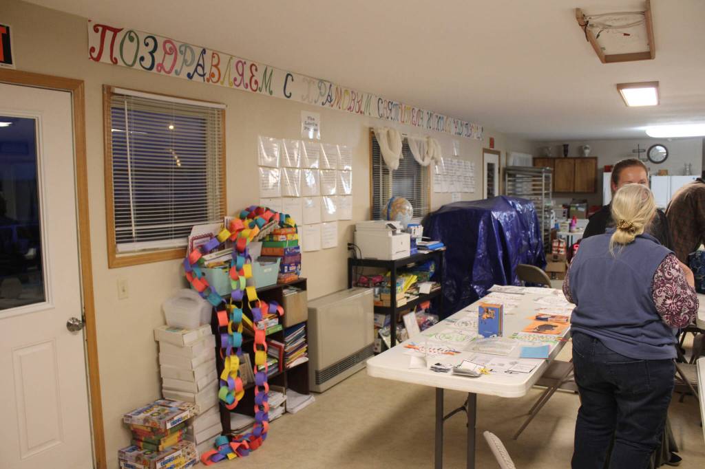 Community members gather in a building part of the Church of St. Nicholas, out of which a school cooperative runs, during a meeting on Tuesday, Oct. 10, 2023 in Nikolaevsk, Alaska. In rear, cars are parked in front of a building that has been used this school year as a makeshift classroom for families who are part of a home-school cooperative. (Ashlyn OHara/Peninsula Clarion)