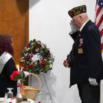 Attendees of a Veterans Day ceremony and potluck place poppies on a symbolic grave at the American Legion Post 20 in Kenai, Alaska, on Saturday, Nov. 11, 2023. (Jake Dye/Peninsula Clarion)