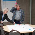Kathy Gensel and Tim Navarre make suggestions on a preliminary route for the Kahtnu Area Transit at the Challenger Learning Center of Alaska in Kenai, Alaska, on Wednesday, Nov. 29, 2023. (Jake Dye/Peninsula Clarion)