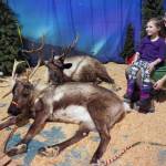 Jenna Bedford, of Kenai Reindeer Farm, sits next to her reindeer with Juliana Bedford during the Fourth Annual Holiday Cheer Christmas Bazaar at the Old Carrs Mall in Kenai, Alaska, on Saturday, Dec. 9, 2023. (Jake Dye/Peninsula Clarion)