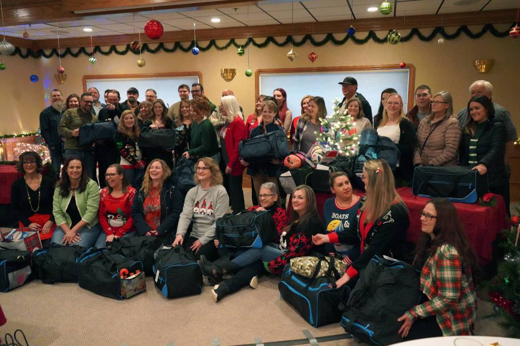 The Kenai Peninsula Association of Realtors sits with duffel bags of Christmas gifts donated to the Kenai Peninsula Borough School Districts Students in Transition program at Kenai Catering in Kenai, Alaska, on Thursday, Dec. 14, 2023. (Jake Dye/Peninsula Clarion)