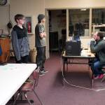 Eli Castro, Blake Gillis and Kaizen Fuller discuss character and map selections with Coach Shane Lopez during their state championship match against Lathrop High School in Super Smash Bros. Ultimate at Kenai Central High School in Kenai, Alaska, on Thursday, Dec. 14, 2023. (Jake Dye/Peninsula Clarion)