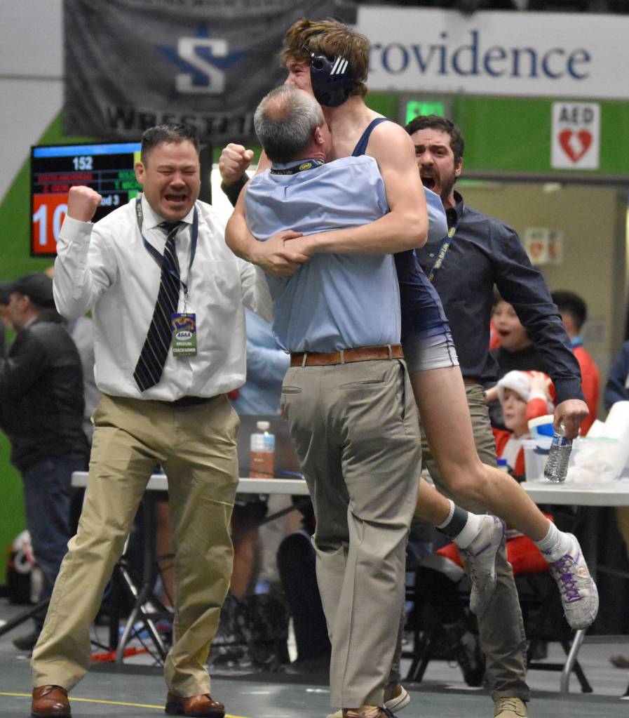 Soldotnas Trevor Michael hugs Soldotna head coach Pete Dickinson as assistants Max LeClair and Phil Leck celebrate. Michael won the Division I state title at 152 pounds by pinning Souths Zane Gerlach on Saturday, Dec. 16, 2023, at the state wrestling tournament at the Alaska Airlines Center in Anchorage, Alaska. (Photo by Jeff Helminiak/Peninsula Clarion)