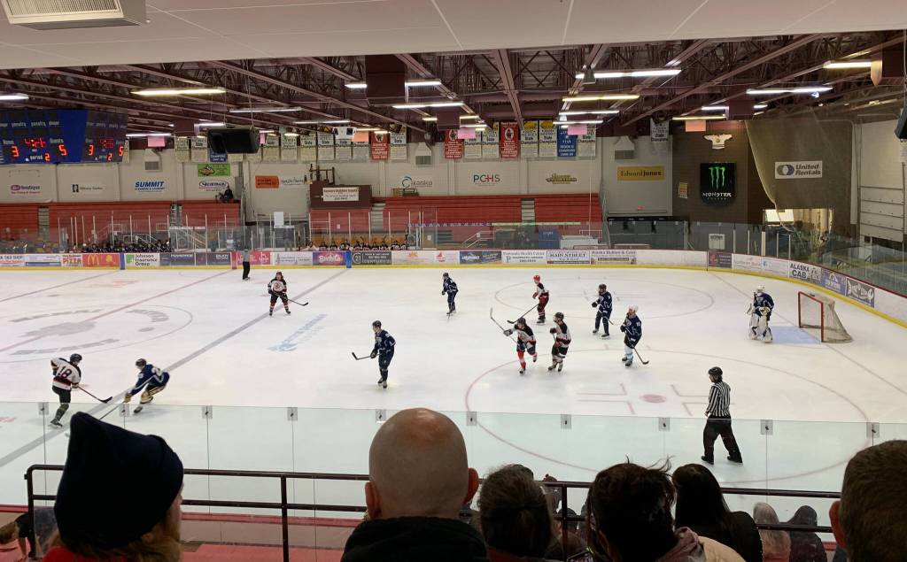 Lower left: 2023 Kenai Central High School alum Gavin Langham (#18) and 2021 Soldotna High School alum Dylan Walton battle over the puck in the second period of the annual Kenai/Nikiski and SoHi/Skyview alumni hockey game at the Soldotna Regional Sports Complex on Friday, Dec. 22, 2023, in Soldotna, Alaska. (Ashlyn OHara/Peninsula Clarion)