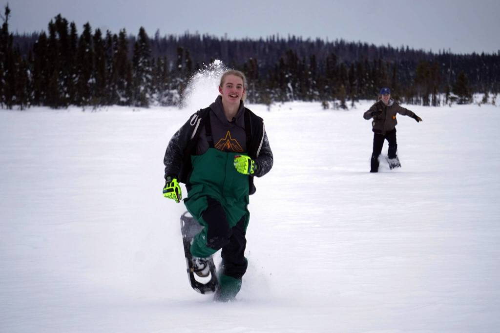 Nathan Teates uses snowshoes to run across Headquarters Lake in the Kenai National Wildlife Refuge, pursued by Isaac Copple, near Soldotna, Alaska, on Saturday, Jan. 6, 2024. (Jake Dye/Peninsula Clarion)