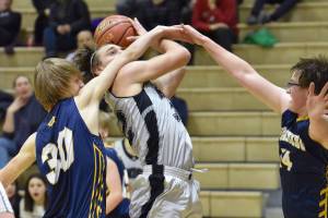Nikiski's Seth Payne drives against Homer's Justice Davidson and Einar Pederson on Friday, Jan. 12, 2024, at Nikiski Middle-High School in Nikiski, Alaska. (Photo by Jeff Helminiak/Peninsula Clarion)
