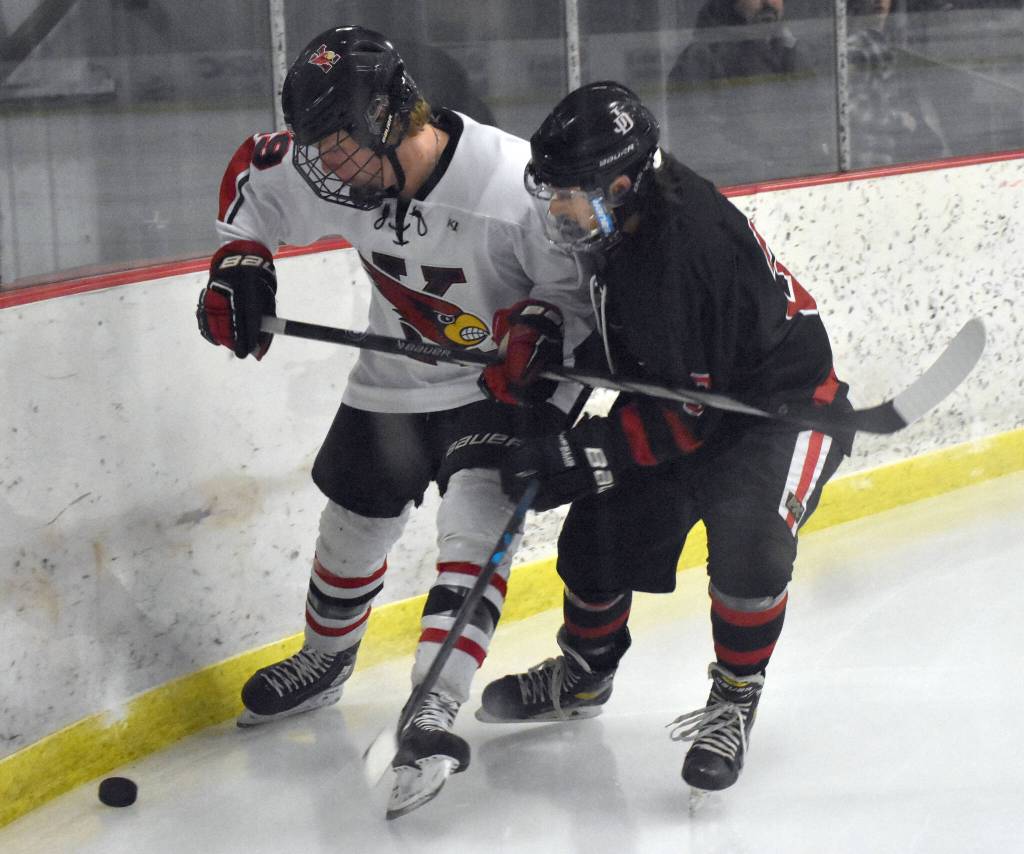 Kenai Centrals Isaac Potton and Juneau-Douglas: Yadaa.at Kales Ian Moller battle for the puck Friday, Jan. 19, 2024, at the Kenai Multi-Purpose Facility in Kenai, Alaska. (Photo by Jeff Helminiak/Peninsula Clarion)