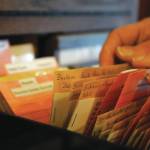 A person peruses packets of seeds in the Soldotna Seed Library at The Goods Sustainable Grocery on Thursday, Feb. 1, 2024. (Jake Dye/Peninsula Clarion)