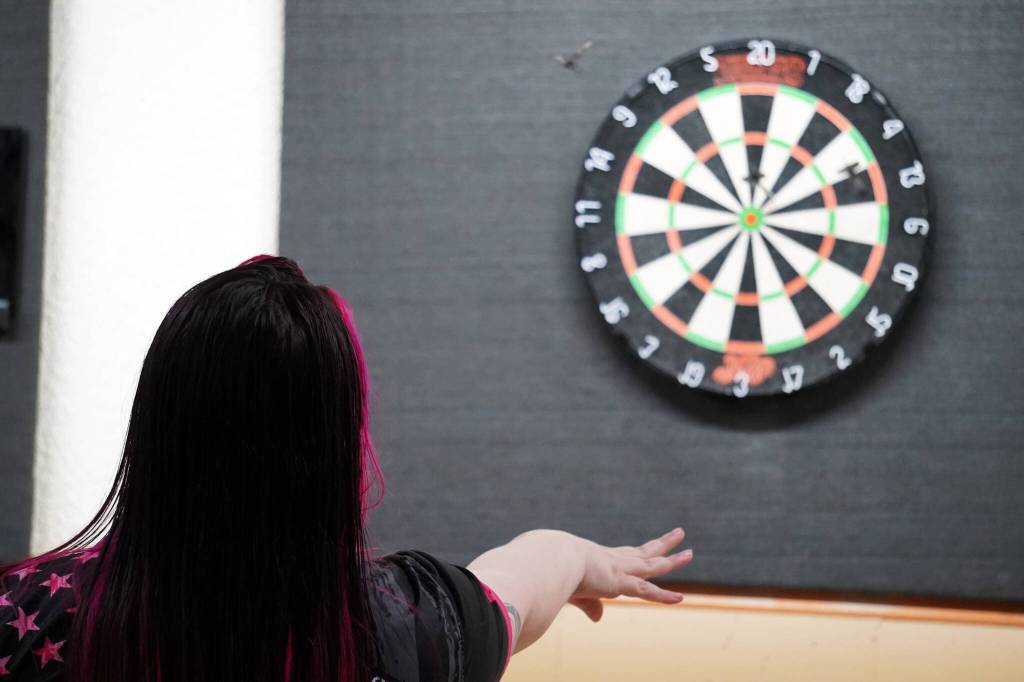Skyler Smith launches a dart at the Elks Lodge in Kenai, Alaska, on Saturday, Feb. 3, 2024. (Jake Dye/Peninsula Clarion)
