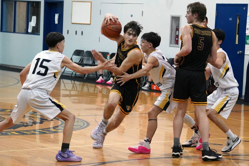 Ninilchiks Rowan Mahoney moves towards the net despite an attempted block by Aniaks Gavin Smith and Troy Morgan during a basketball game at Ninilchik School in Ninilchik, Alaska, on Wednesday, Feb. 14, 2024. (Jake Dye/Peninsula Clarion)