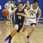 Homers Lucas Story dribbles away from Sewards Ben Ambrosiani on Saturday, March 9, 2024, at the Peninsula Conference tournament at Homer High School in Homer, Alaska. (Photo by Jeff Helminiak/Peninsula Clarion)