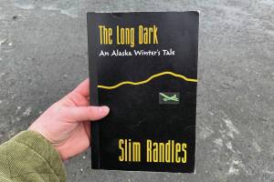 A copy of Slim Randles The Long Dark: An Alaska Winters Tale is held on Wednesday, April 27, 2024, near Soldotna, Alaska. (Ashlyn OHara/Peninsula Clarion)