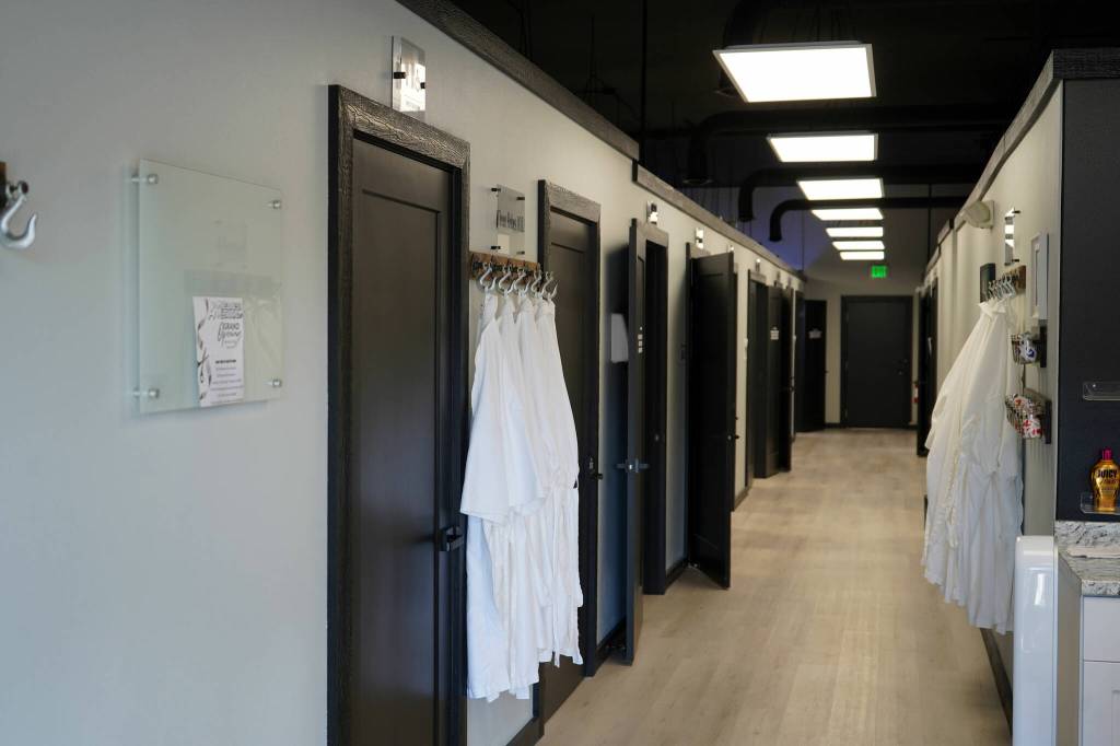 A hallway is lined with rooms and robes at AK Wellness & Tanning in Kenai, Alaska, on Saturday, April 6, 2024. (Jake Dye/Peninsula Clarion)