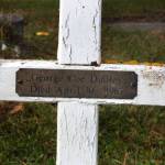 This white, wooden cross and small brass plate in the Kenai City Cemetery mark the last resting place of George Coe Dudley. Getting him into the grave turned out to be no simple task. (Clark Fair photo)