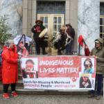 Advocates on behalf of missing and murdered Indigenous persons hold a banner and perform a opening song during a rally in front of the Alaska State Capitol on Sunday, May 5, 2024, to commemorate the annual Missing and Murdered Indigenous Persons Awareness Day. (Mark Sabbatini / Juneau Empire)
