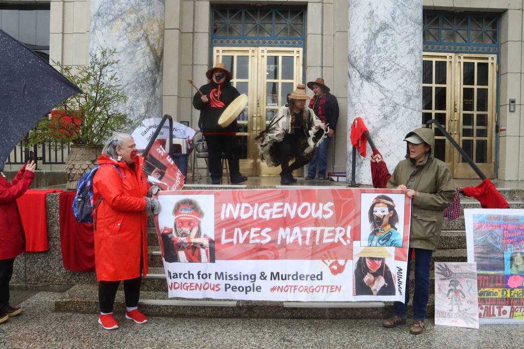Advocates on behalf of missing and murdered Indigenous persons hold a banner and perform a opening song during a rally in front of the Alaska State Capitol on Sunday, May 5, 2024, to commemorate the annual Missing and Murdered Indigenous Persons Awareness Day. (Mark Sabbatini / Juneau Empire)