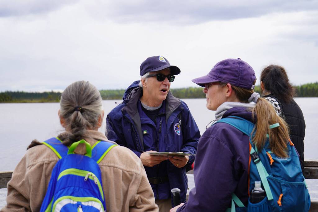 A guide from the Kenai National Wildlife Refuge leads visitors on a hike of Centennial Trail that concluded at Headquarters Lake near Soldotna, Alaska, on Saturday, June 1, 2024. (Jake Dye/Peninsula Clarion)