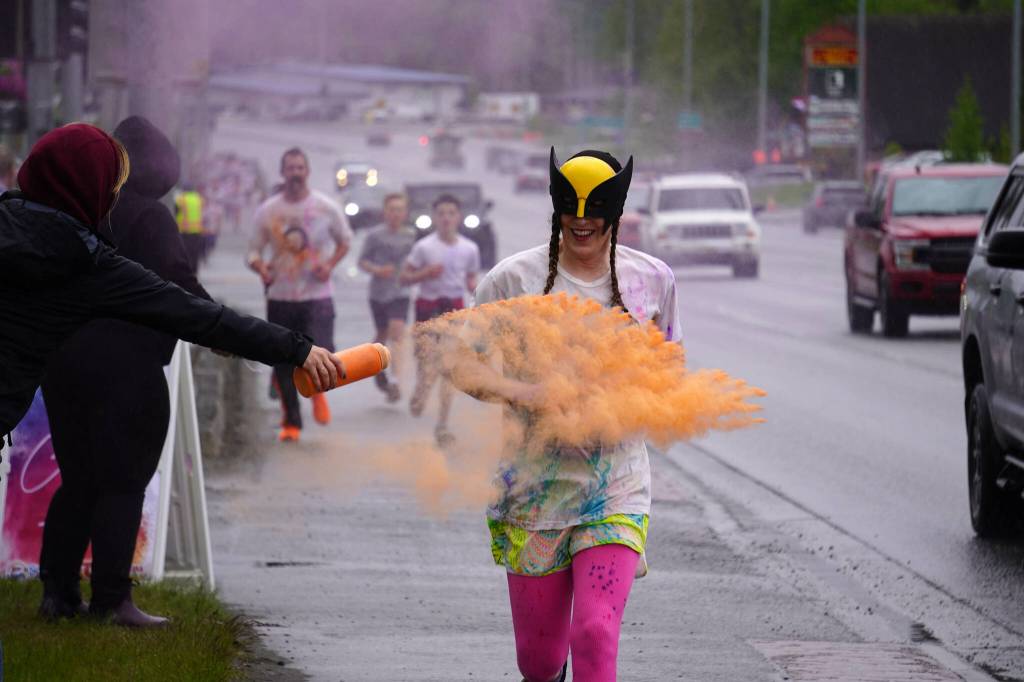 Attendees brave orange colored powder during a color run as part of the opening night of the Levitt AMP Soldotna Music Series along the Sterling Highway in Soldotna, Alaska, on Wednesday, June 5, 2024. (Jake Dye/Peninsula Clarion)