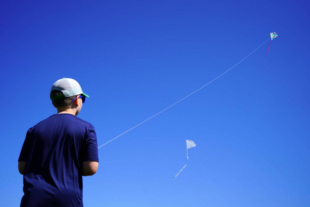 Nathan Nelson directs a kite flying dozens of feet up in the sky above Millennium Square in Kenai, Alaska, during the Kenai Kite Festival on Saturday, June 15, 2024. (Jake Dye/Peninsula Clarion)