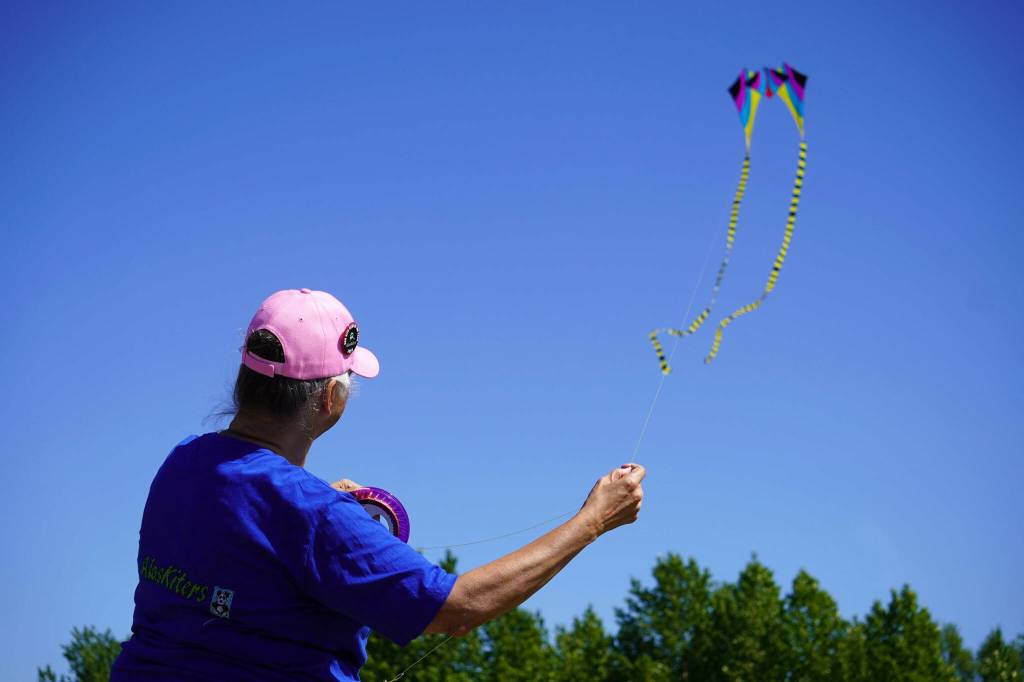 Suzanne Taylor directs a kite flying in the sky above Millennium Square in Kenai, Alaska, during the Kenai Kite Festival on Saturday, June 15, 2024. (Jake Dye/Peninsula Clarion)