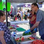 Rep. Ben Carpenter, R-Nikiski, right, slices and serves fresh watermelon during North Peninsula Recreation Service Areas Family Fun in the Midnight Sun at the Nikiski Community Recreation Center in Nikiski, Alaska, on Saturday, June 15, 2024. (Jake Dye/Peninsula Clarion)