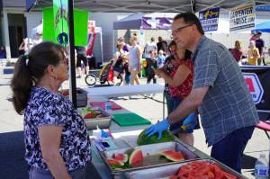 Rep. Ben Carpenter, R-Nikiski, right, slices and serves fresh watermelon during North Peninsula Recreation Service Areas Family Fun in the Midnight Sun at the Nikiski Community Recreation Center in Nikiski, Alaska, on Saturday, June 15, 2024. (Jake Dye/Peninsula Clarion)