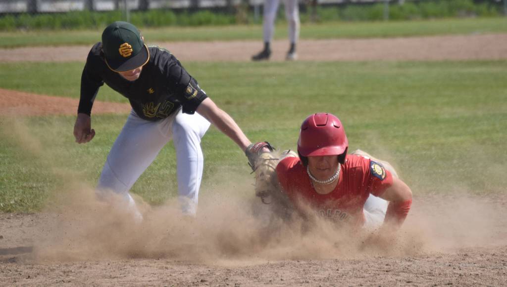 Napoleon (Ohio) River Bandits player Kadyn Radzik dives back into first safely in front of Service first baseman Owen Hickman in the final of the Lance Coz Wood Bat Tournament on Monday, June 24, 2024, at Coral Seymour Memorial Park in Kenai, Alaska. (Photo by Jeff Helminiak/Peninsula Clarion)