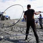 A fisher carries two sockeye salmon up and out of the water during the opening day of the personal use dipnet fishery at the mouth of the Kasilof River in Alaska, on Tuesday, June 25, 2024. (Jake Dye/Peninsula Clarion)