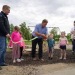 Children help City of Kenai Mayor Brian Gabriel cut the ribbon at an event celebrating the installation of a new inclusive seesaw at Kenai Municipal Park in Kenai, Alaska, on Thursday, June 27, 2024. (Jake Dye/Peninsula Clarion)