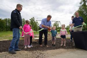Children help City of Kenai Mayor Brian Gabriel cut the ribbon at an event celebrating the installation of a new inclusive seesaw at Kenai Municipal Park in Kenai, Alaska, on Thursday, June 27, 2024. (Jake Dye/Peninsula Clarion)