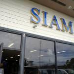 A sign is illuminated above the entrance of Siam Noodles and Food in Kenai, Alaska, during their grand opening on Tuesday, July 2, 2024. (Jake Dye/Peninsula Clarion)