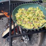 Scrambled eggs with diced zucchini, kielbasa sausage and broccoli florets cooked over a firepit make a hearty and doable outdoors meal. (Photo by Tressa Dale/Peninsula Clarion)